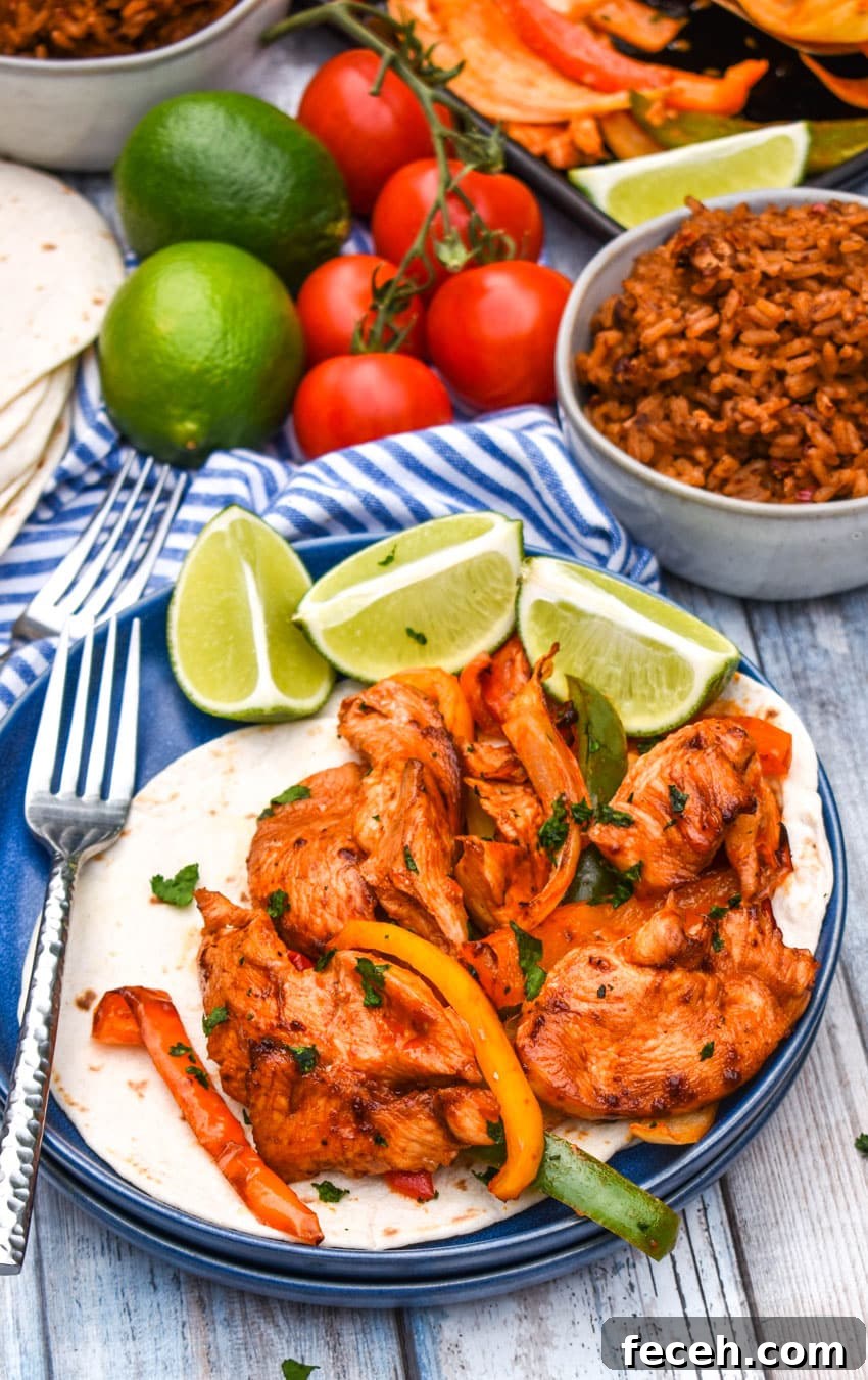 sheet pan chicken fajitas mixture on flour tortillas on a blue plate with fresh lime wedges on the side