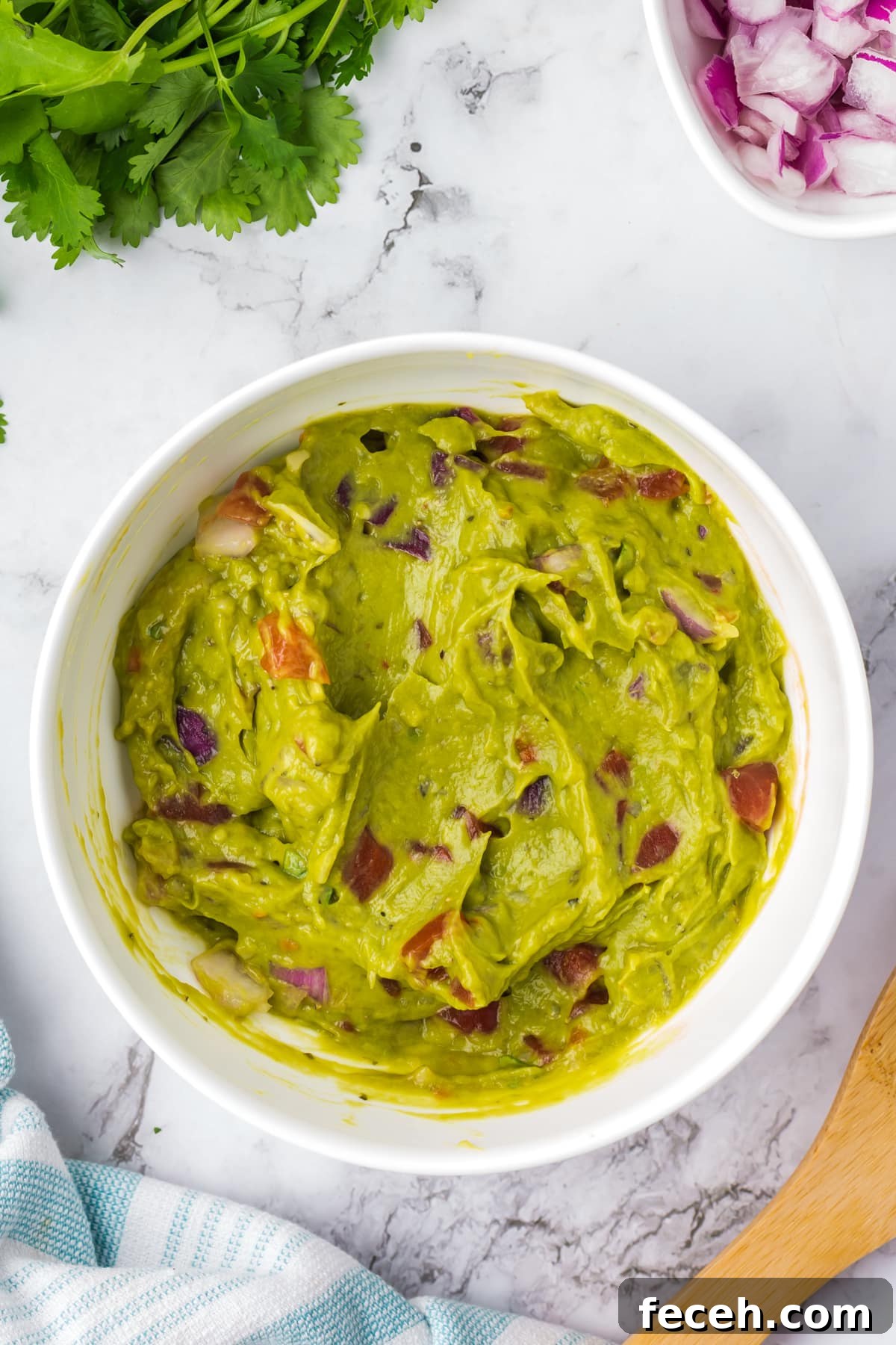 A bowl of guacamole featuring chunks of tomato.