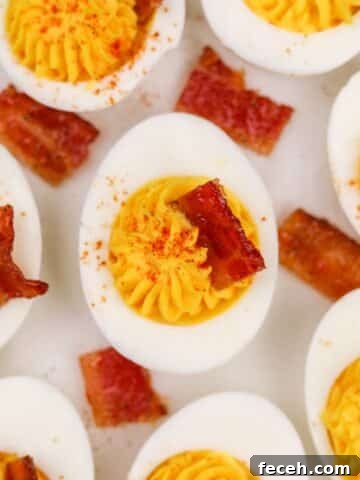 8 deviled egg halves topped with a square of bacon.