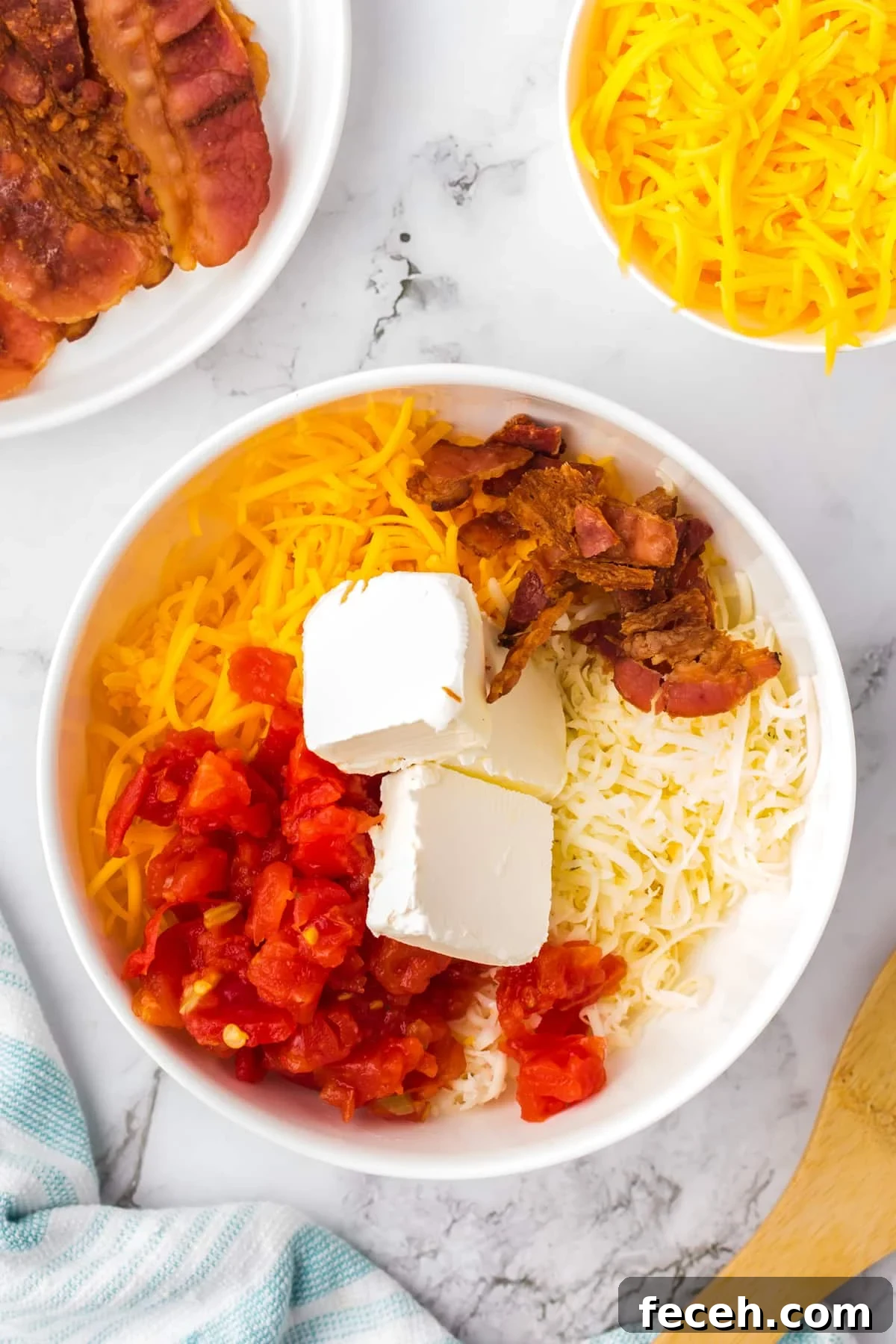 A large bowl filled with cheese, bacon, cream cheese, and rotel tomatoes.