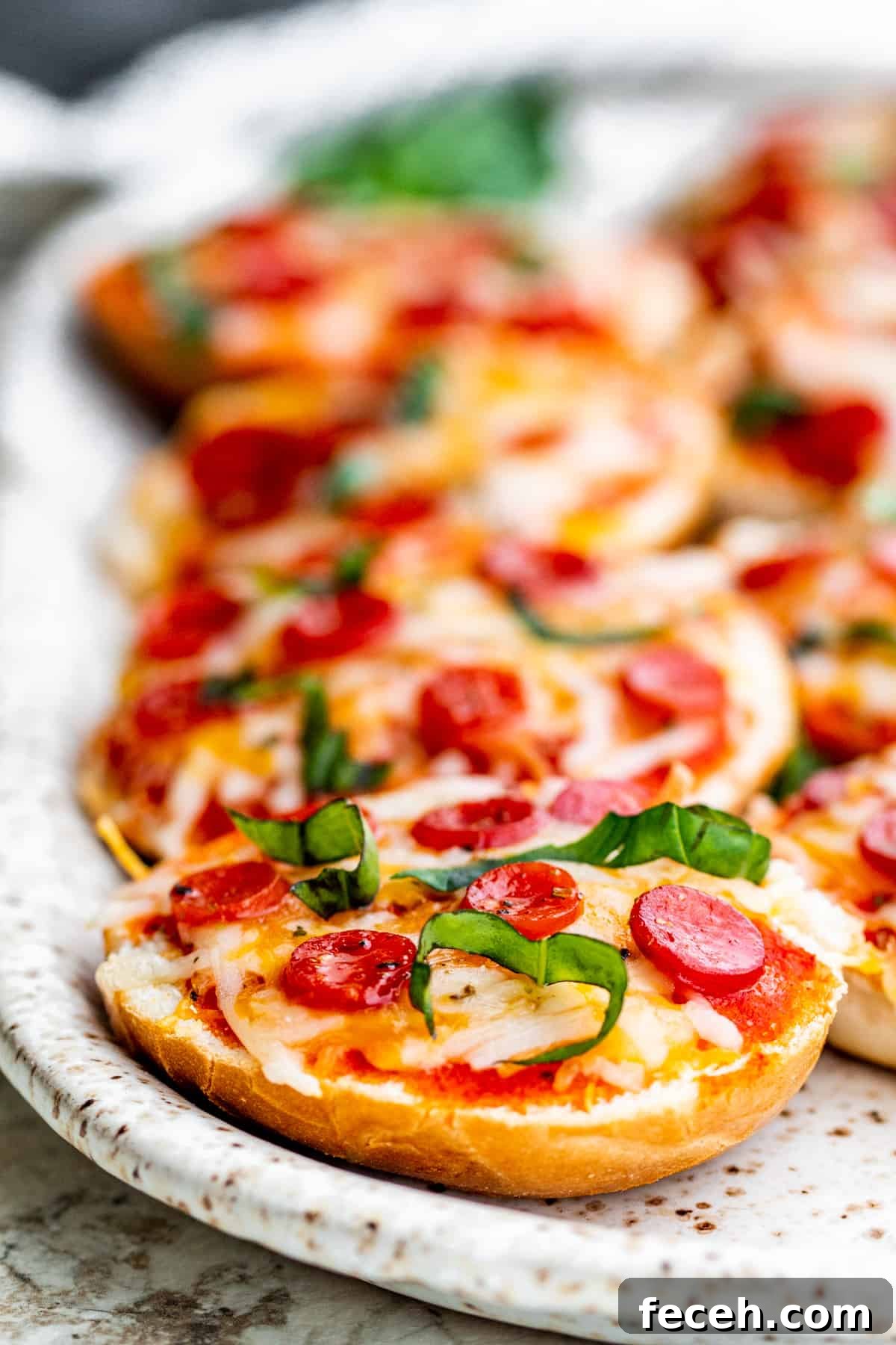 Straight on shot of pizza bagels on white serving tray.