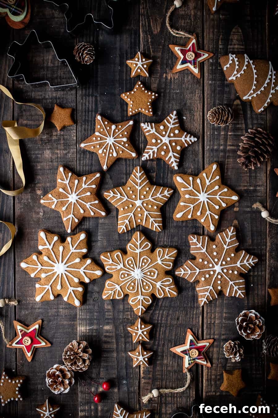 Vegan gingerbread snowflake cookies arranged in a christmas tree shape with pine cones and christmas decorations.