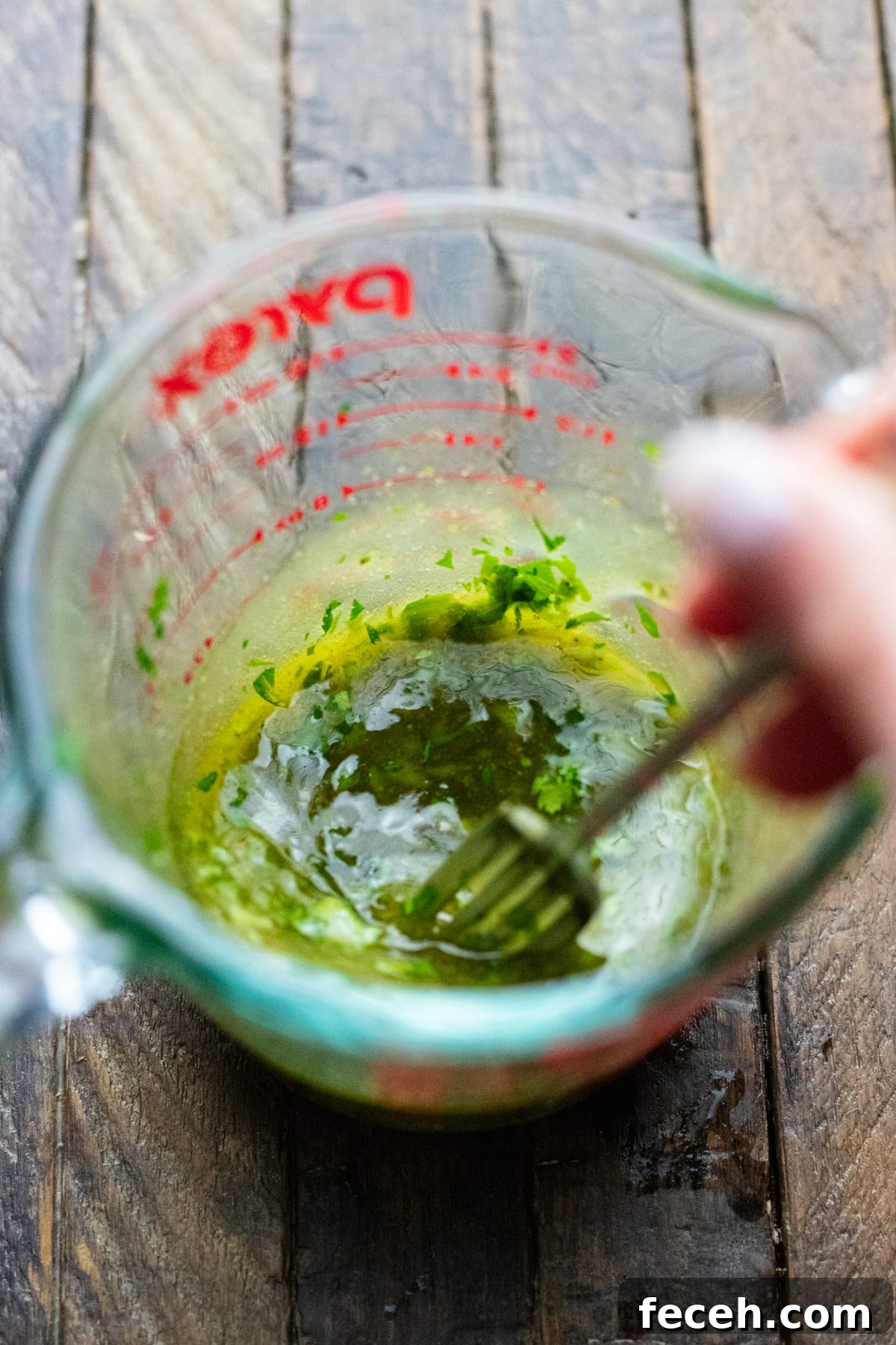 Vegetarian Taco Salad with Cilantro-Lime Dressing Recipe 4 A hand using fork to whisk dressing in liquid measuring cup.