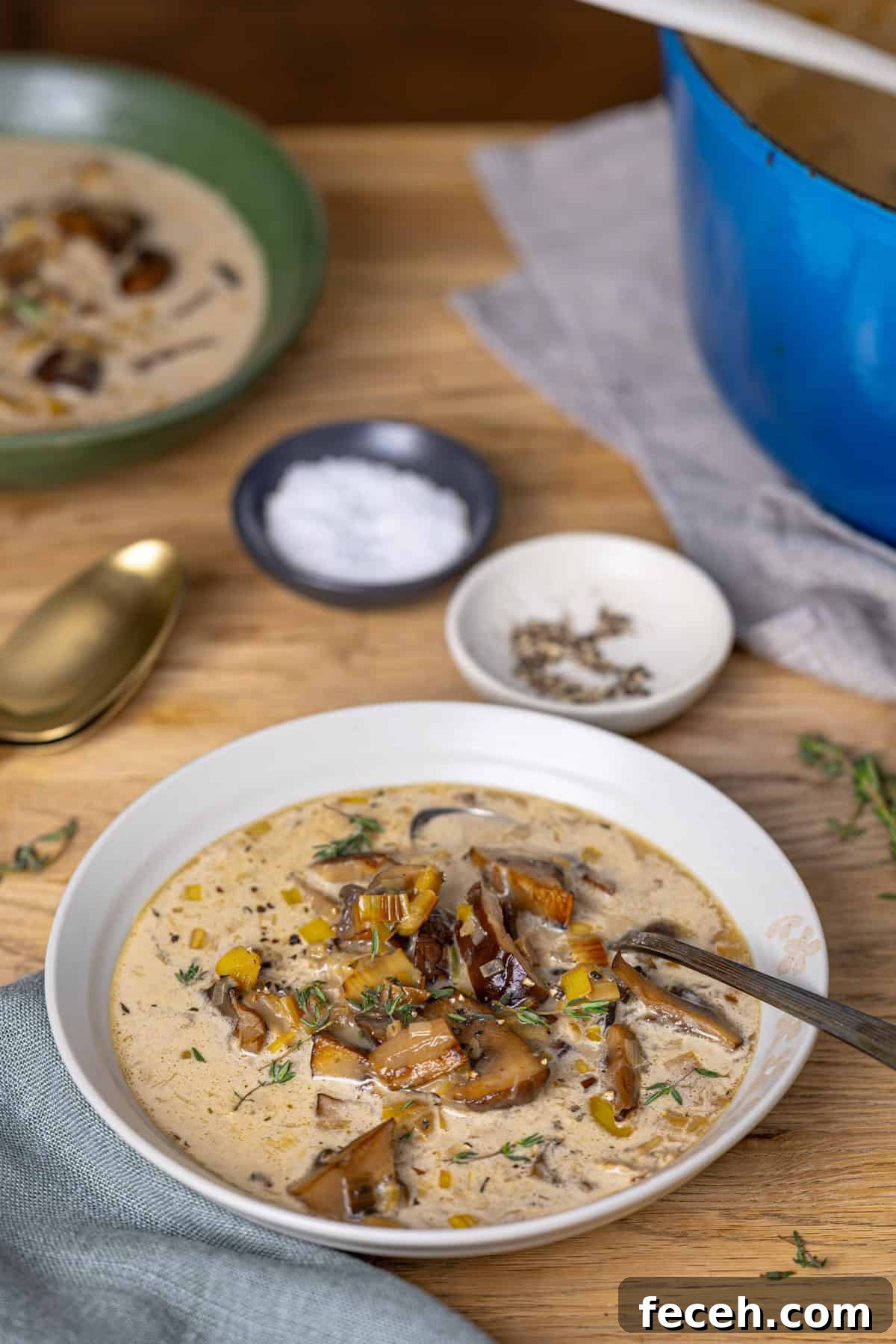 A table with mushroom leek soup bowls and salt and pepper to the side.
