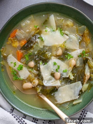 A bowl of escarole and white bean soup with parmesan cheese for garnish.