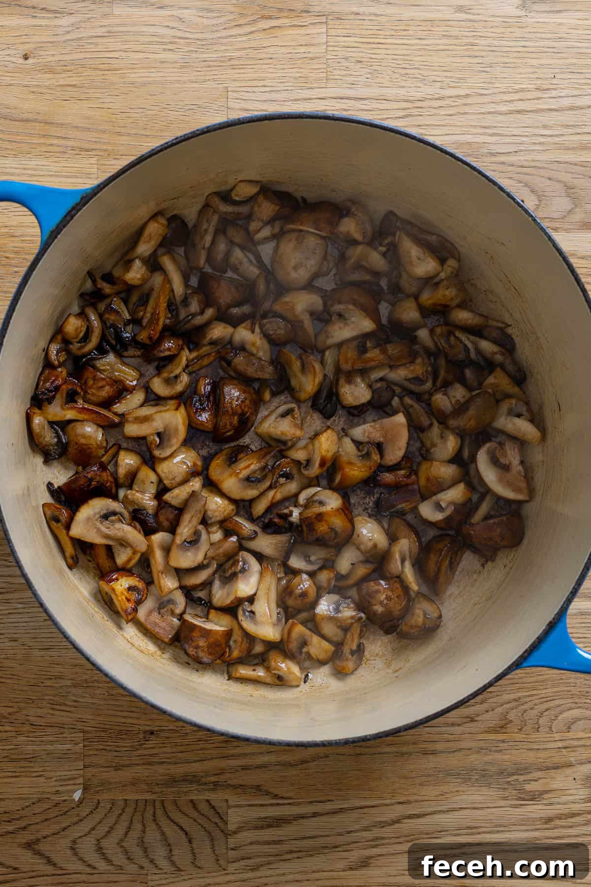 Mushrooms cooking in a large dutch oven.