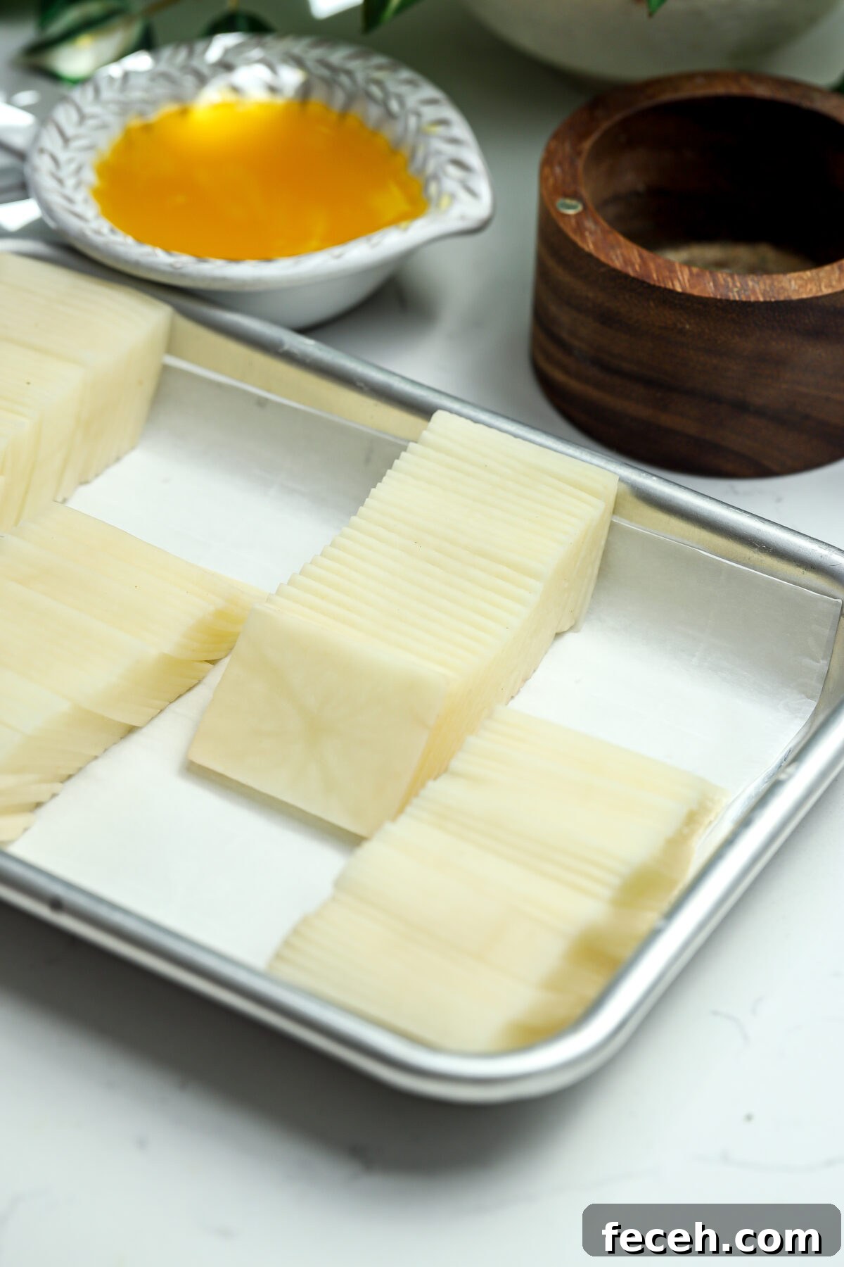 A tray lined with parchment paper holds stacks of square thinly sliced Russets.
