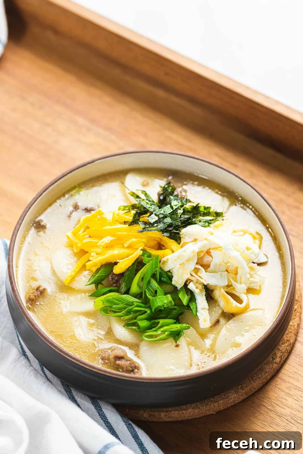 Tteokguk or Korean rice cake soup in beef broth garnished with eggs, seaweed, and green onions.