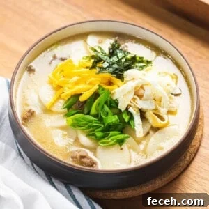 Tteokguk or Korean rice cake soup in beef broth garnished with eggs, seaweed, and green onions.