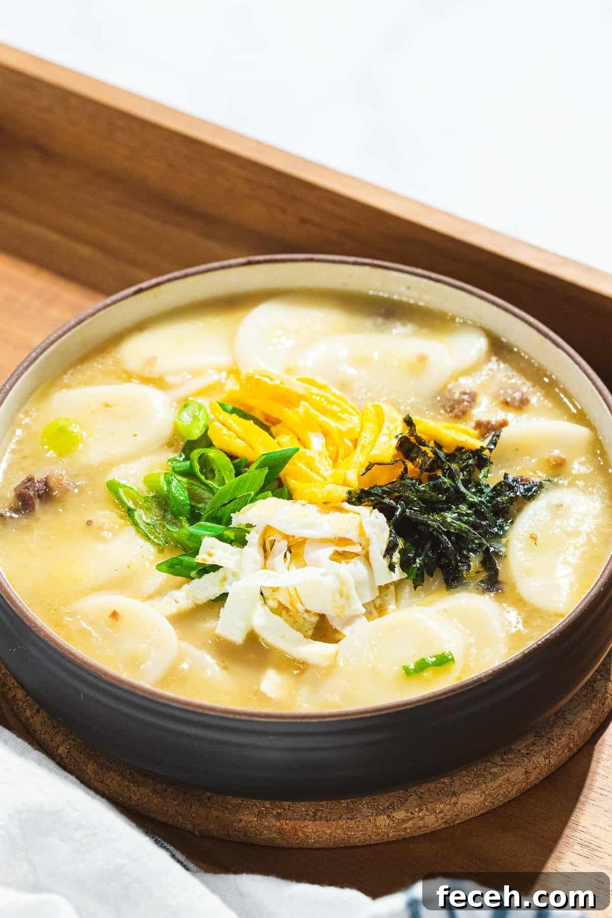 Tteokguk or Korean rice cake soup garnished with eggs, seaweed, and scallions.