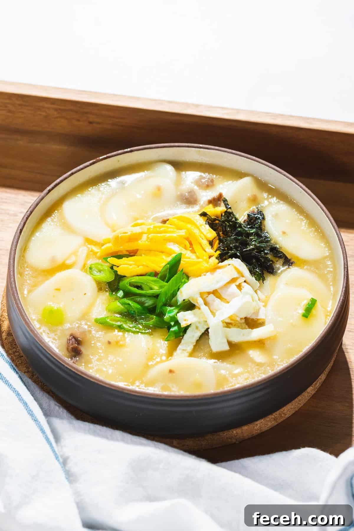 Tteokguk or Korean rice cake soup in a beef broth garnished with eggs, seaweed, and green onions.