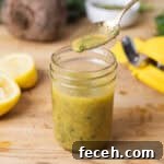 A glass jar of lemon Dijon dressing on Butcherblock countertop.