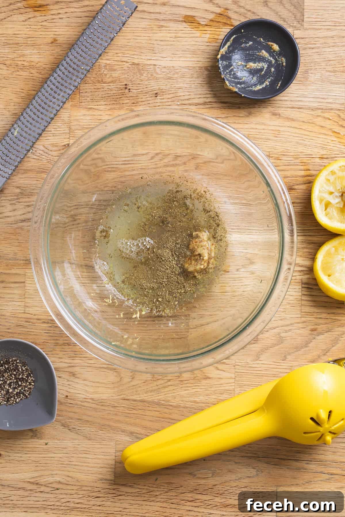 Lemon juice, lemon zest, and other ingredients in a glass bowl for a vinaigrette.