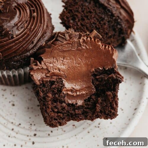 A chocolate cupcake sliced in half, showing a chocolate filling.