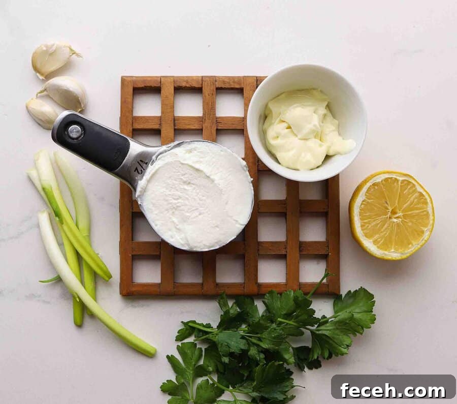 Quick Greek Yogurt Ranch Dip Ready in 5 Minutes 3 Yogurt, mayo, lemon, garlic, scallions, and parsley laid out on a table.