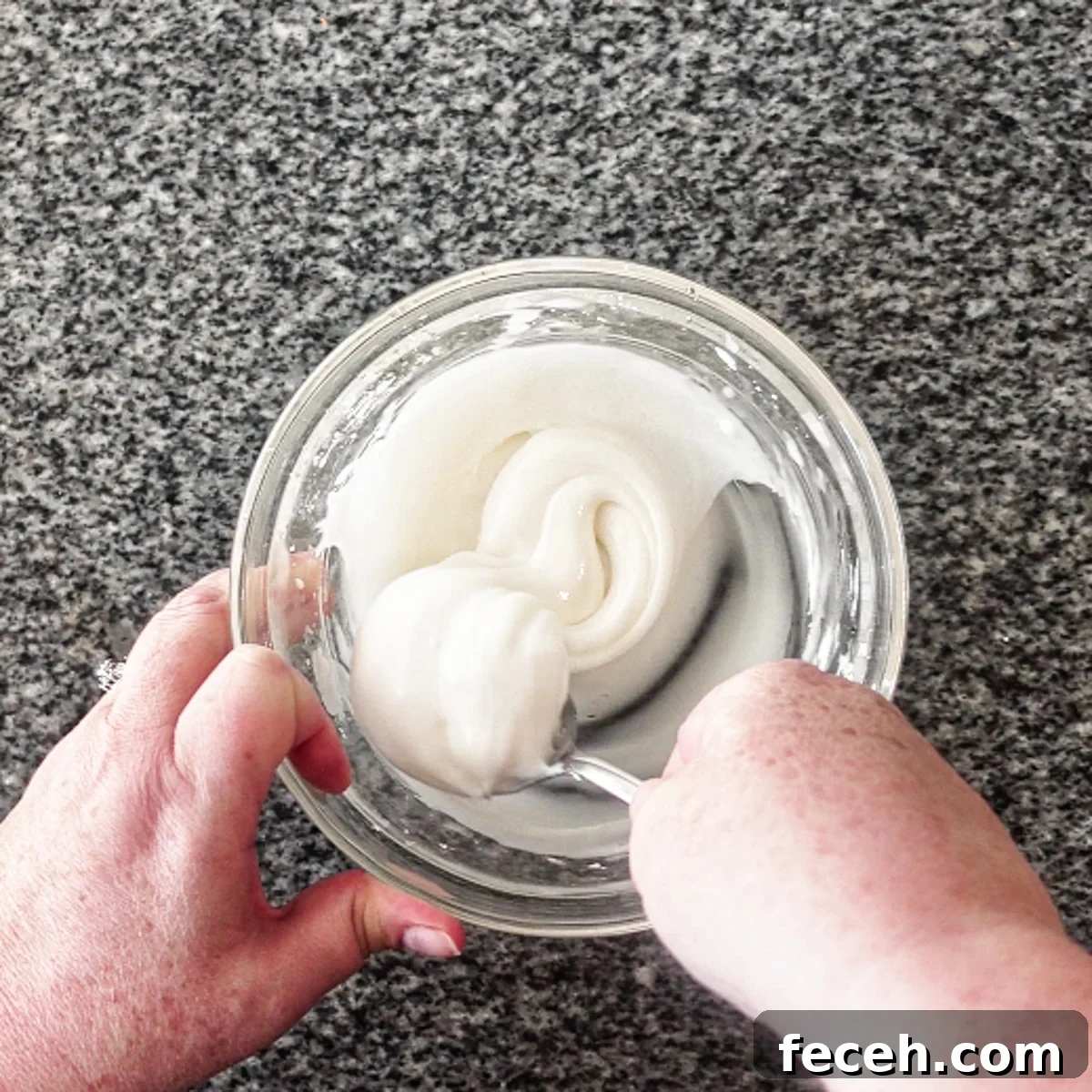 stirring icing ingredients in small glass bowl with spoon.