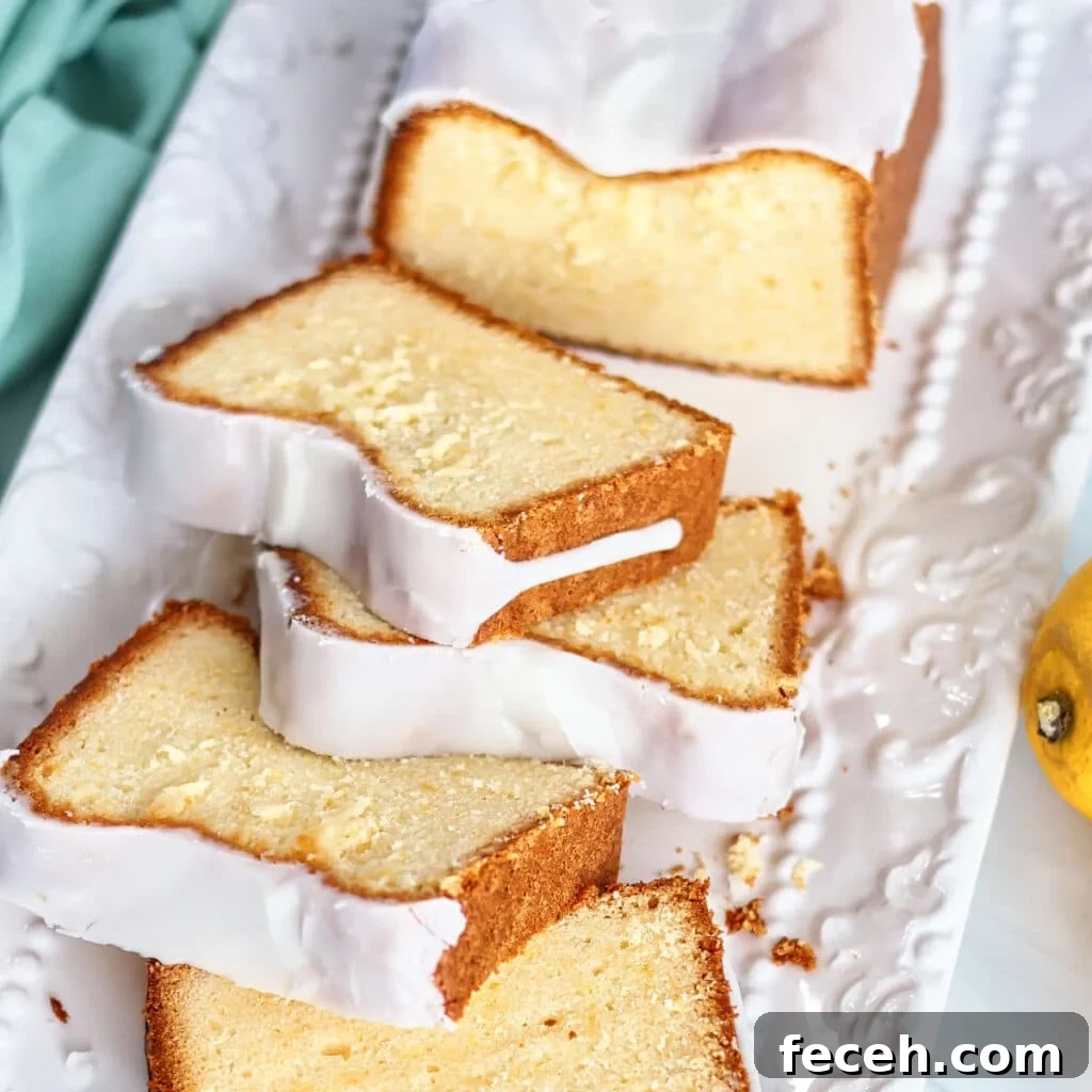 slice of lemon loaf cake on a white decorative plate with fork cutting through.