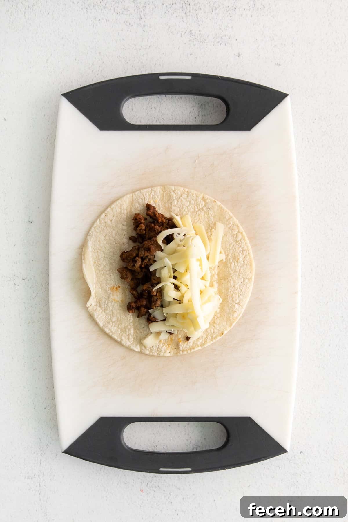 Ground beef and shredded cheese on a corn tortilla.