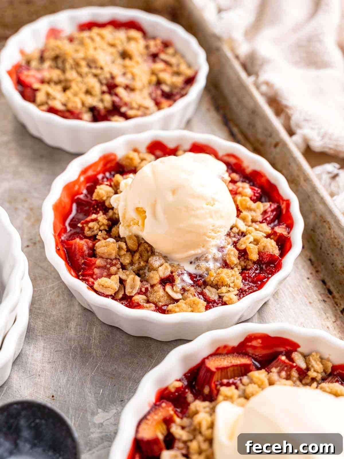 Strawberry rhubarb crisps in ramekins topped with vanilla ice cream.