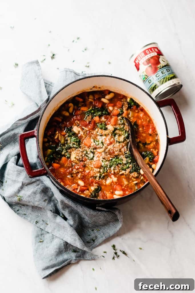 Large cooking pot with wooden spoon stirring minestrone vegetable soup.