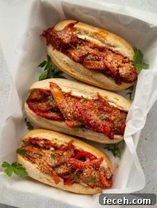Sausage and Peppers Sandwich overhead shot of 3 sausage pepper sandwiches in large baking dish garnished with fresh parsley