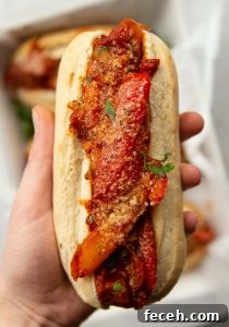Sausage and Peppers Sandwich overhead shot of hand holding sausage peppers sandwich showing filling