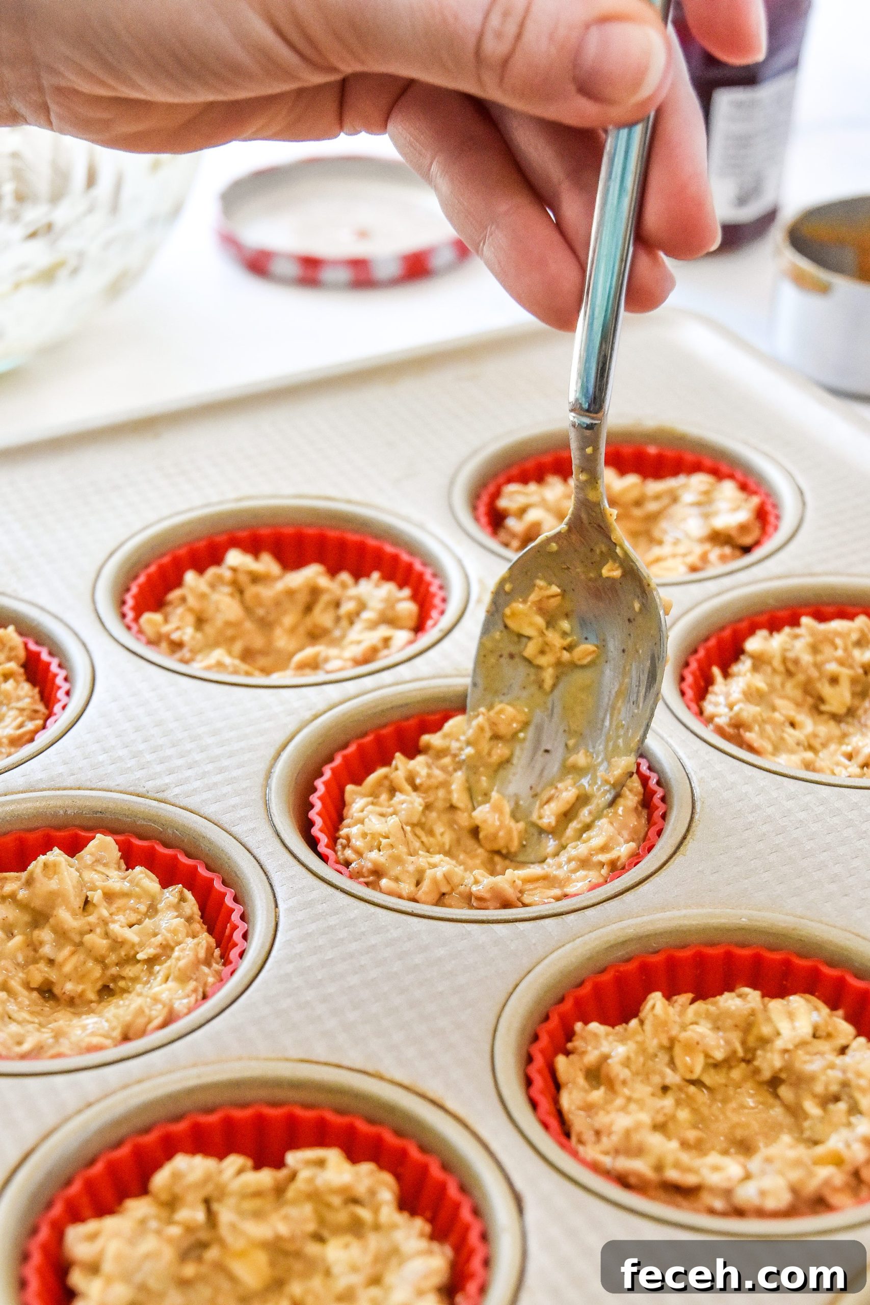 using a spoon to press oatmeal up the sides of the muffin tin.
