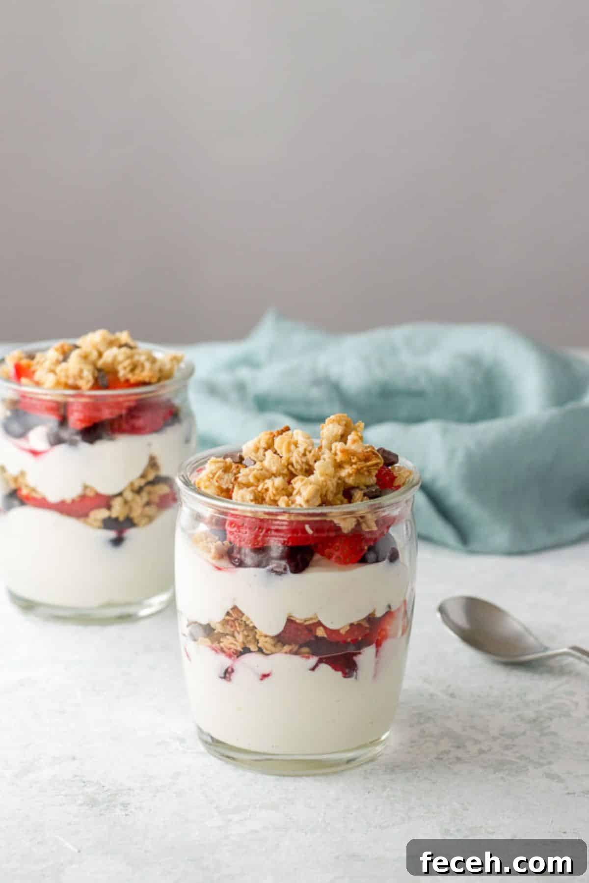 Two glasses of layered yogurt with berries and granola on the table