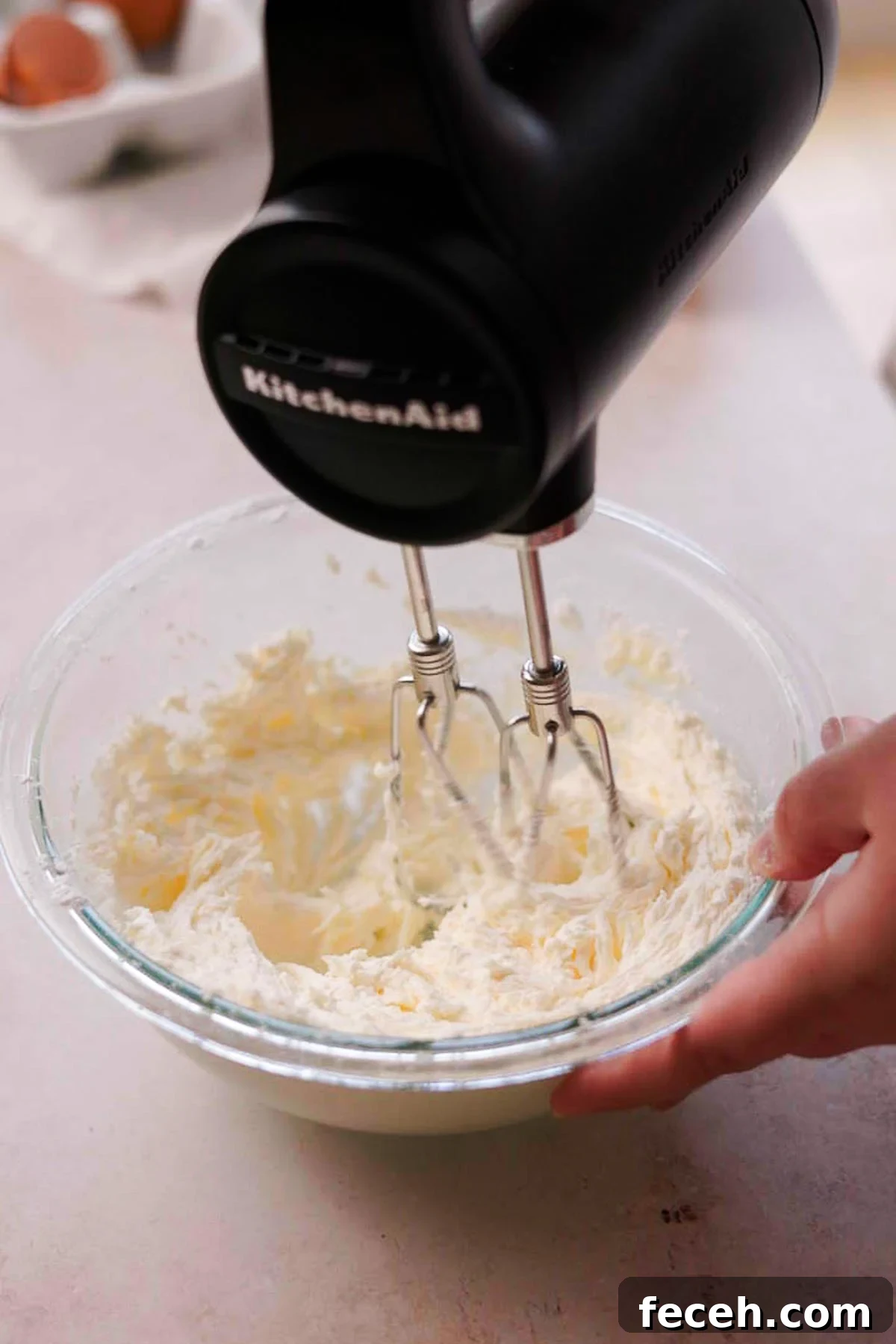 beating butter and powdered sugar together in a bowl with electric mixer