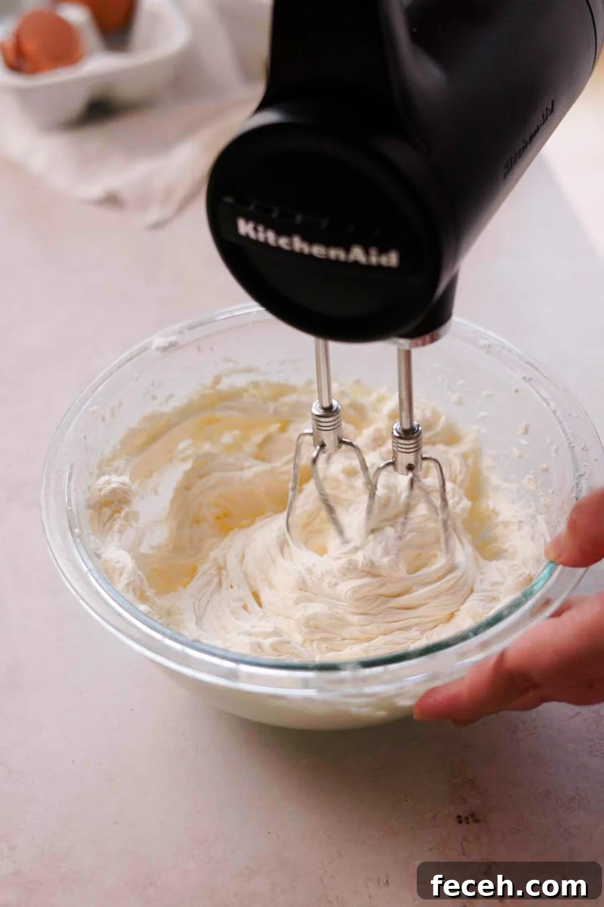 beating sour cream frosting in a bowl with electric mixer