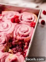 raspberry rolls in pan with gooey filling at the bottom of the pan
