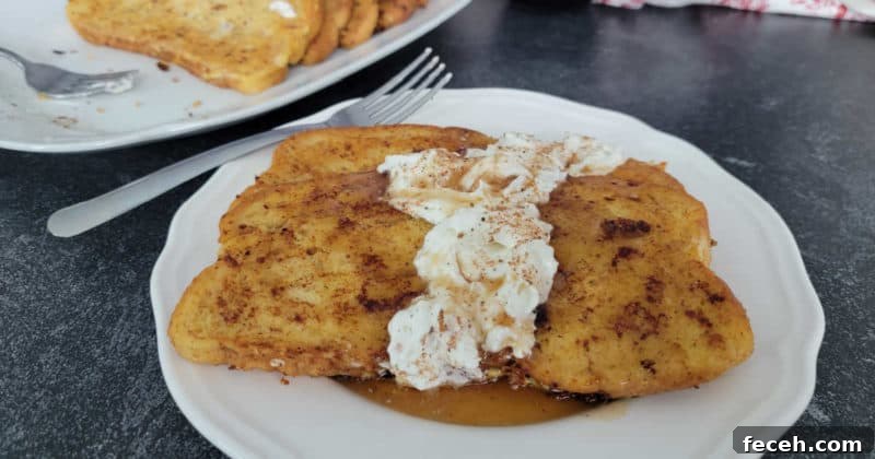 Eggnog French Toast with Eggnog Whipped Cream on a white plate with a silver fork