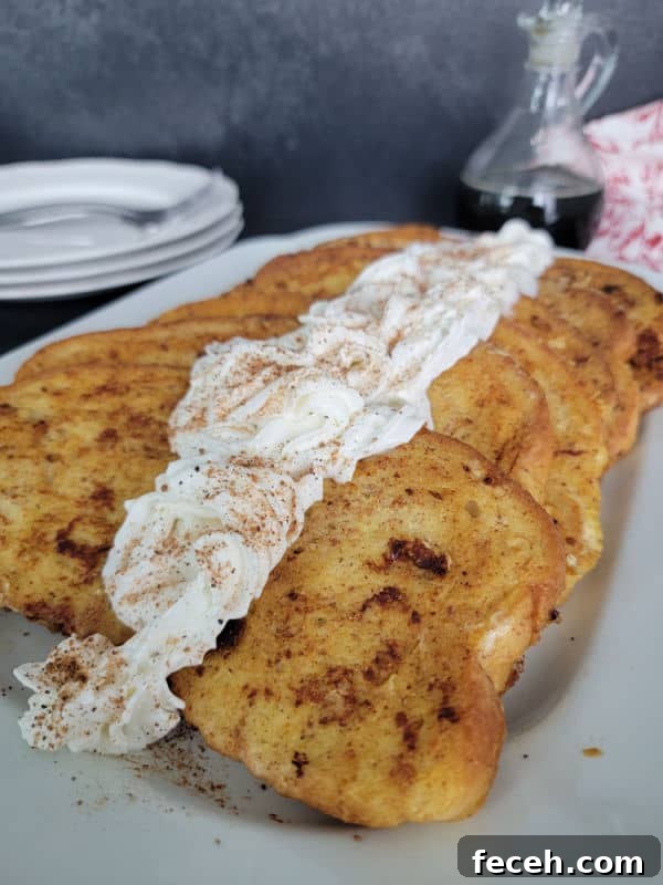 Eggnog French Toast slices on a white plate garnished with eggnog whipped cream and cinnamon/nutmeg