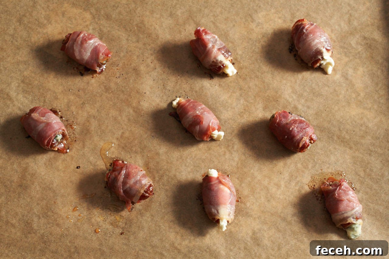 Prosciutto-Wrapped Dates with Goat Cheese and Honey Drizzle 7 Baked prosciutto wrapped dates on a sheet pan.