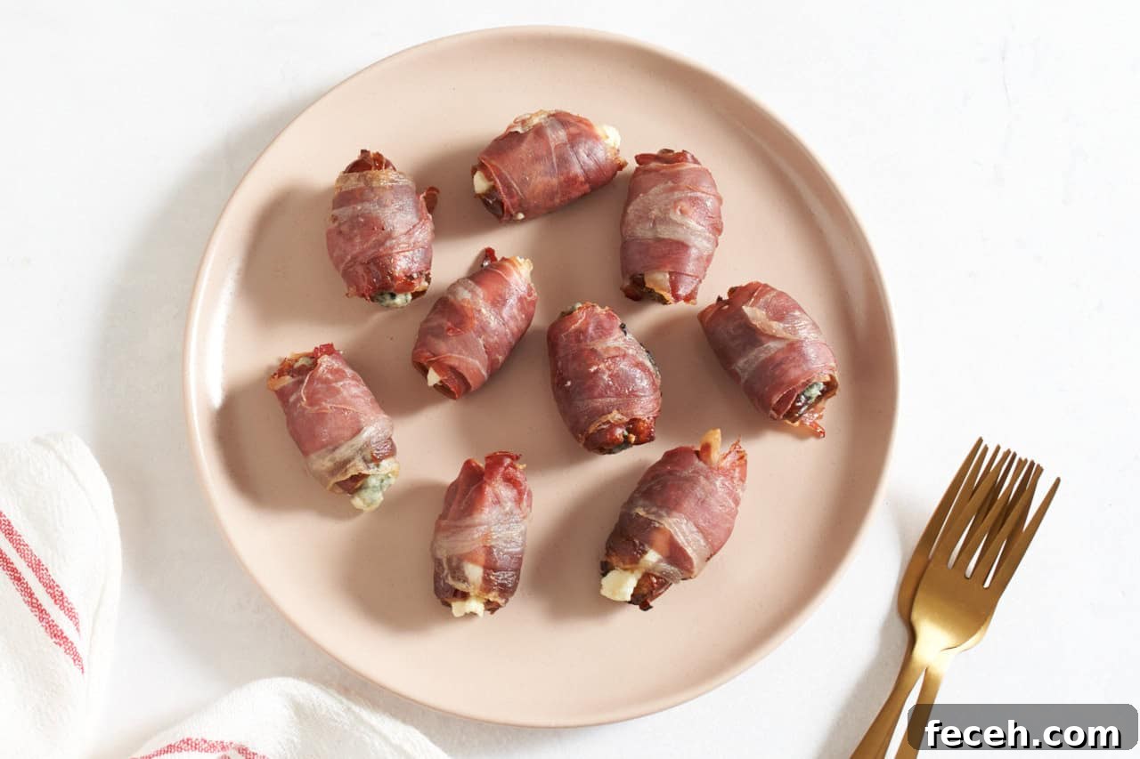 Prosciutto-Wrapped Dates with Goat Cheese and Honey Drizzle 8 Prosciutto wrapped dates stuffed with goat cheese on a pink plate, gold forks are on the right.