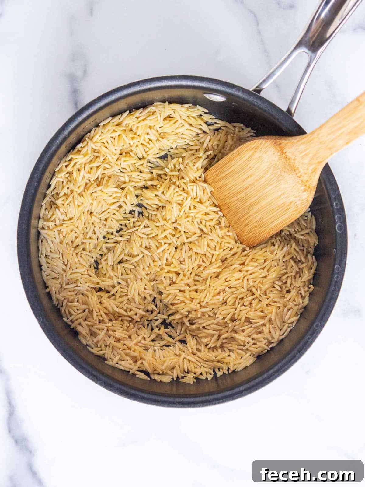 Uncooked orzo coated in butter in a medium saucepan.