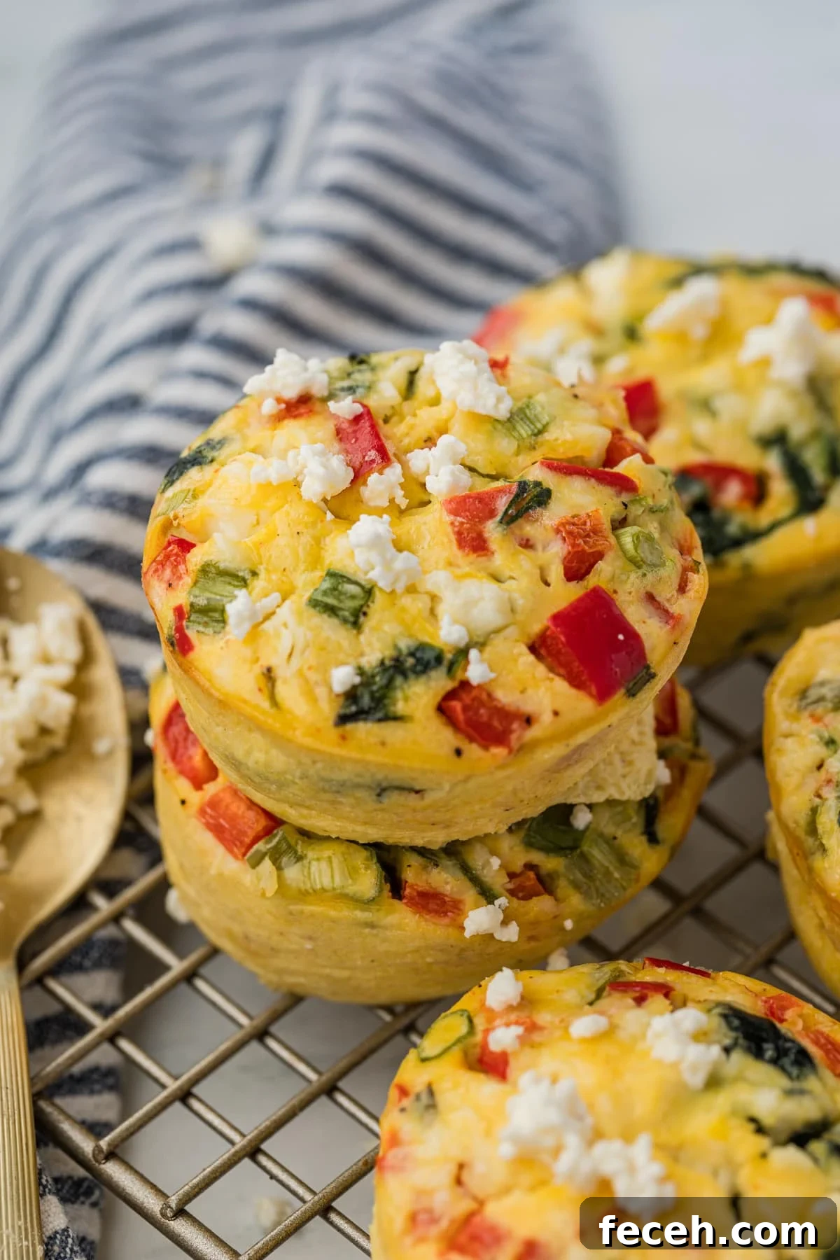 Mini Spinach and Feta Frittatas Recipe 2 Two egg muffins stacked on top of each other on top of a wire cooling rack.