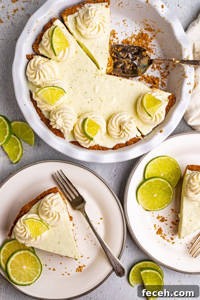 Overhead shot of the best key lime pie. 2 slices of pie have been removed from the pie and are on plates. The remaining pie is in the background with a pie server.