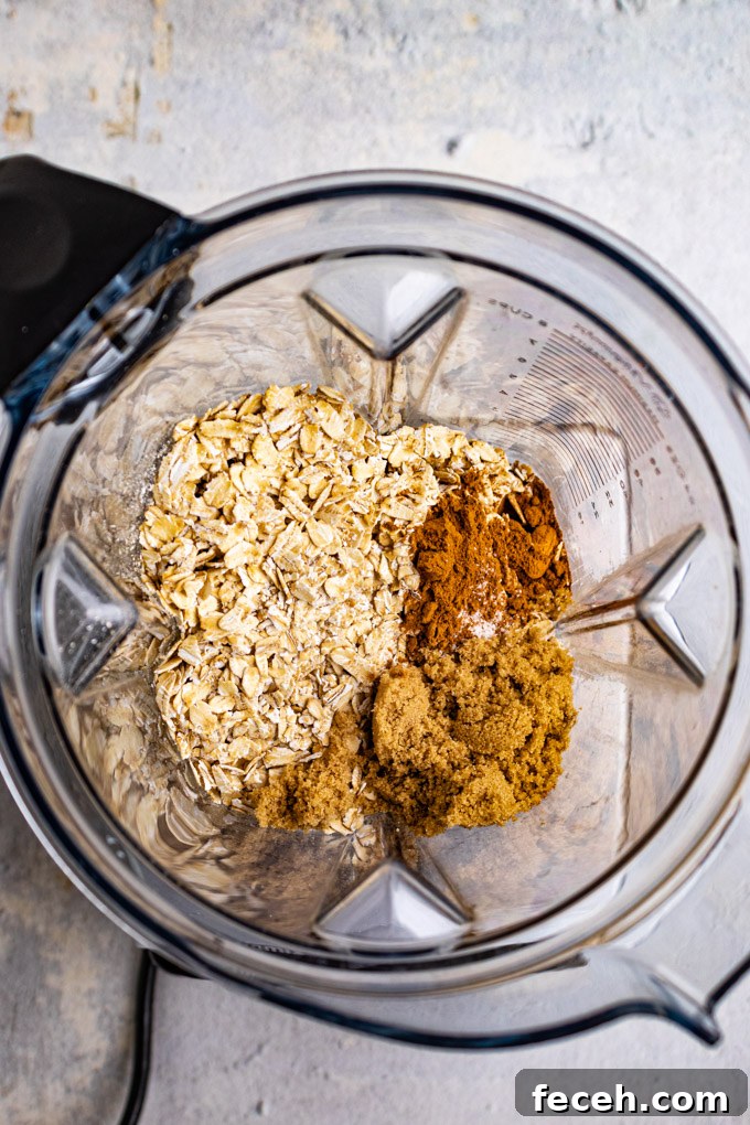 Overhead shot of oats, almonds, brown sugar, and cinnamon in blender - ingredients for a crust.