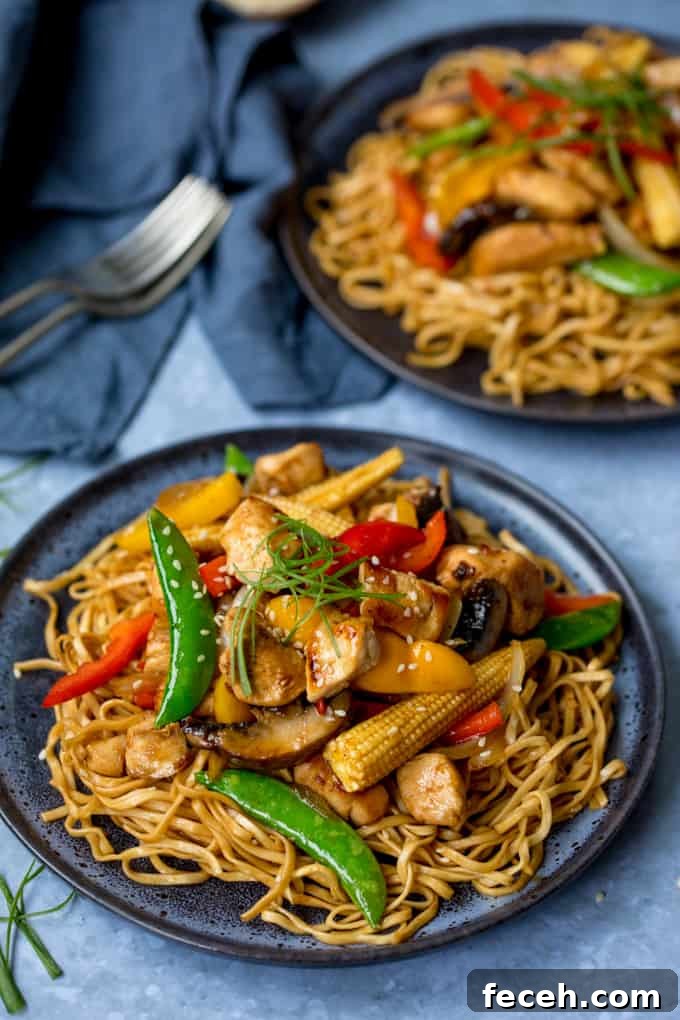 Plate of honey and soy chicken stir fry with noodles, further plate in background