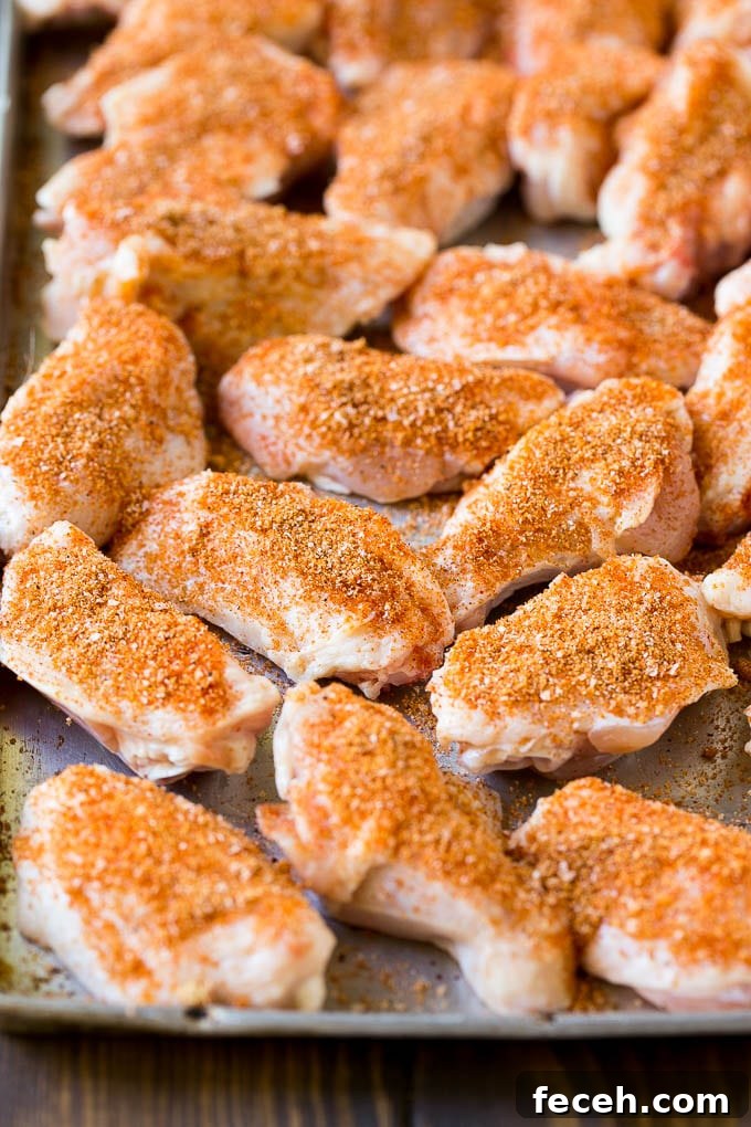 Raw chicken wings coated in homemade spice rub on a sheet pan.