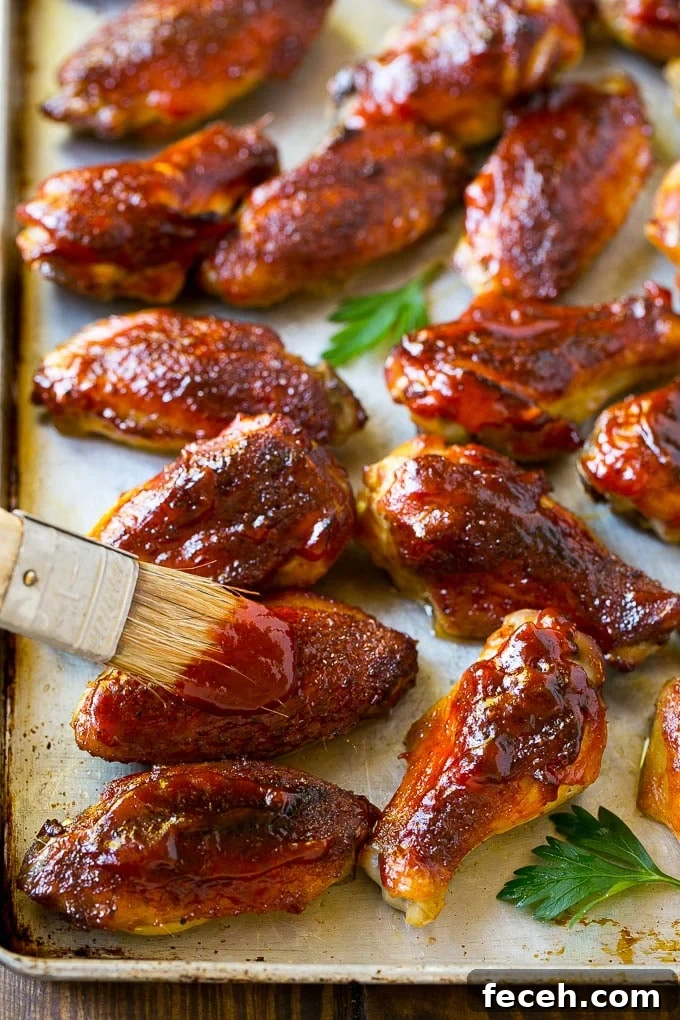 BBQ sauce brushed onto a sheet pan of smoked chicken wings.