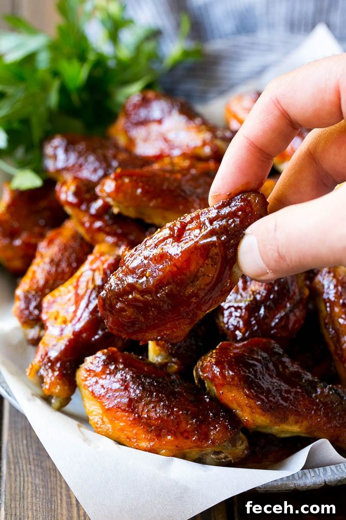 A pile of smoked chicken wings with a hand reaching out for one.