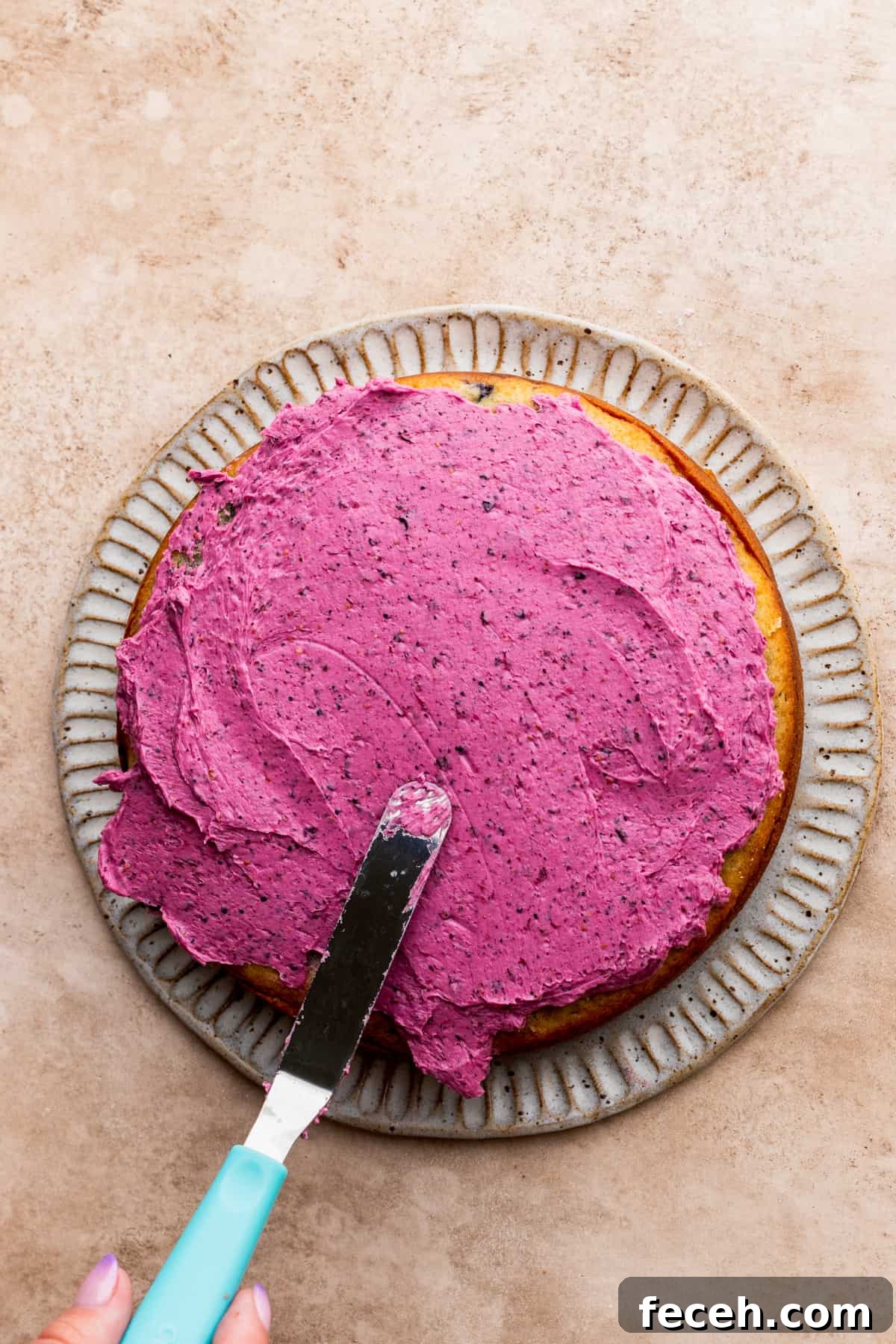 Spreading frosting on top of a cake layer.