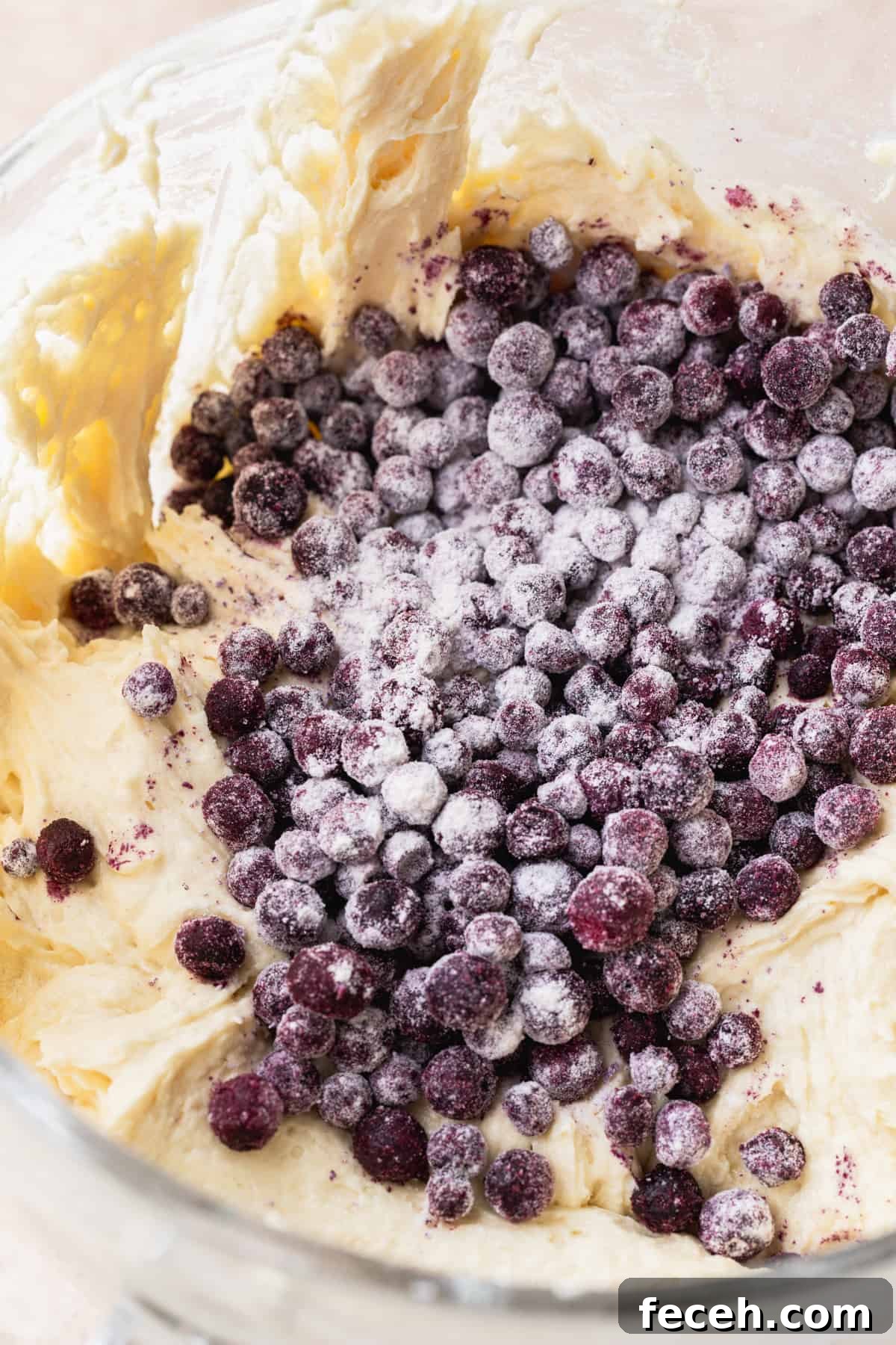 Blueberries on top of batter in a glass bowl.