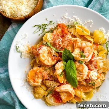 A bowl of shrimp with goat cheese over shell pasta.