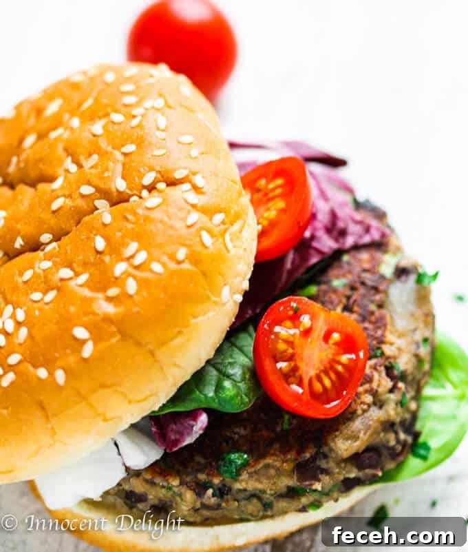 Mushroom Veggie Burger with black beans, topped with spinach and tomatoes on a bun 