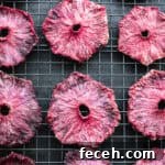Oven dried pink pineapple rings on a wire rack — deep magenta, chewy, and caramelized after 8 hours.