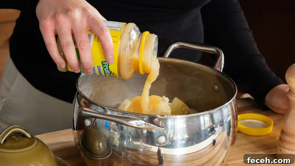 Adding apple sauce to a pot of mashed potatoes–a secret twist that balances everything.