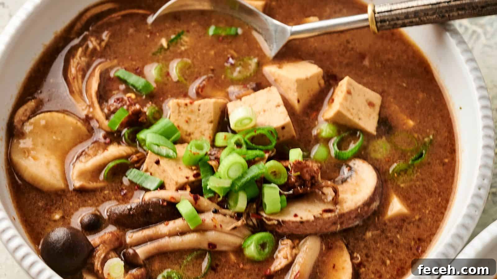 31 Asian Weeknight Dinners to Make Mealtime Exciting 19 Bowl of hot and sour soup with mushrooms, tofu, and sliced green onions, with a spoon on the side.